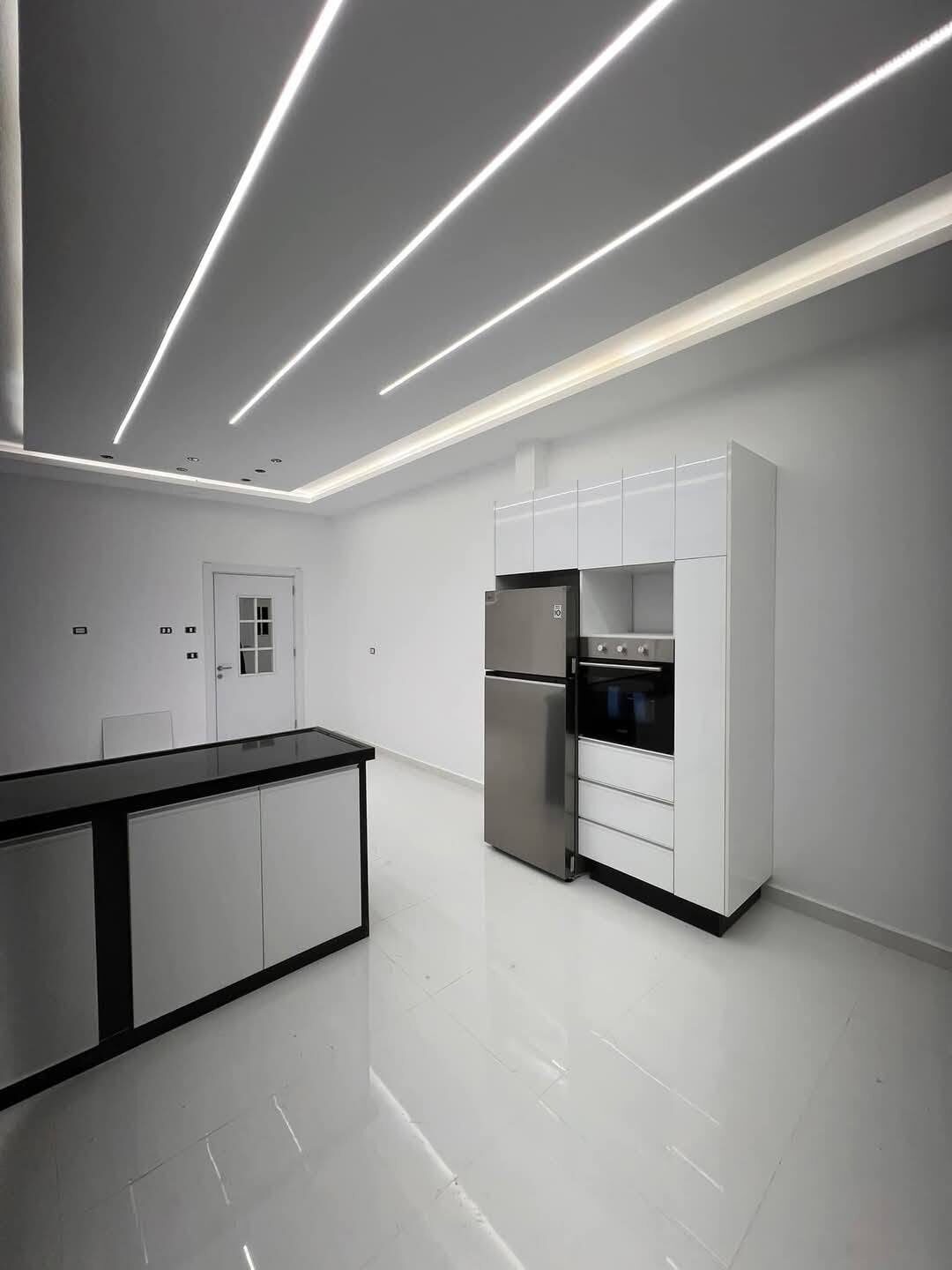 Cuisine minimaliste blanche avec îlot central et plafond LED — réalisation à Tanger